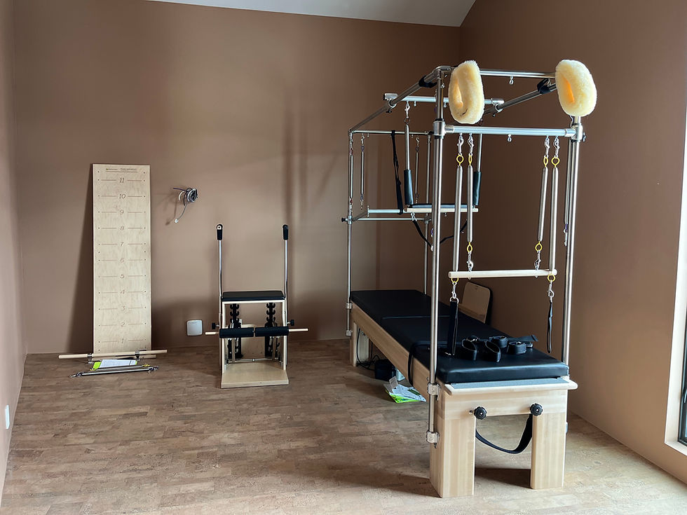 Fully equipped Pilates studio with Cadillac apparatus and chair for therapeutic and fitness training.
