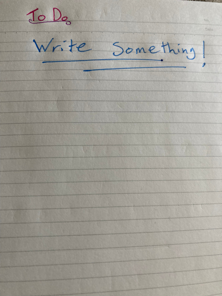 A page of paper, lined in grey without margins, and indented from the pressure of a pen on previous pages. At the top of the page are the words "To Do" in clear and confident pink lettering, underlined with a scroll of purple. Beneath this, covering several lines without really sitting on any of them, are the words "Write Something!" in a bright, sparkly, slightly frenetic blue scrawl. This is underlined twice in slashes of blue. The rest of the page is blank.