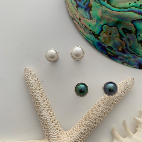 Pearl earrings by Megan Dickens set amongst a flat lay of coastal treasures.