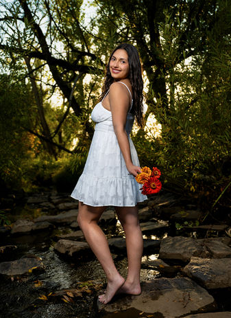 fun high school senior portrait girl posing in creek holding flowers in Superior, Colorado.