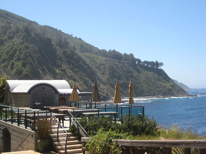 View of the Esalen Institute massage deck, showing massage tables, the upstairs bathhouse and the coast in the background