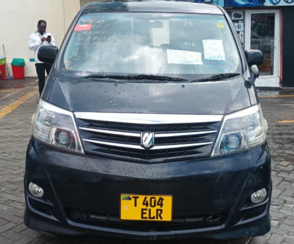 White Toyota Alphard Min Van parked on a sunny day near the coast.