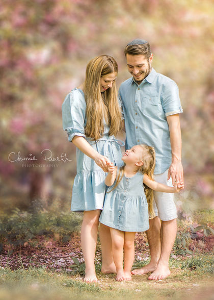 Family of three holding hands in a flower field during family photo shoot with Chunmie Paneth Photography