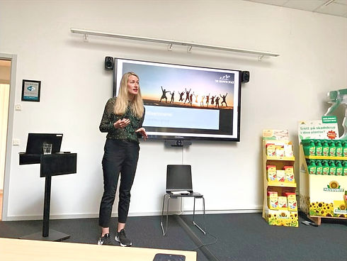 Föreläsare står framför skärm och pratar på ett företag