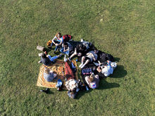 Overhead of a group of people laying together on grass.