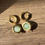 Thumbnail: Gold hoop earrings with green crackle glass beads on wooden surface.
