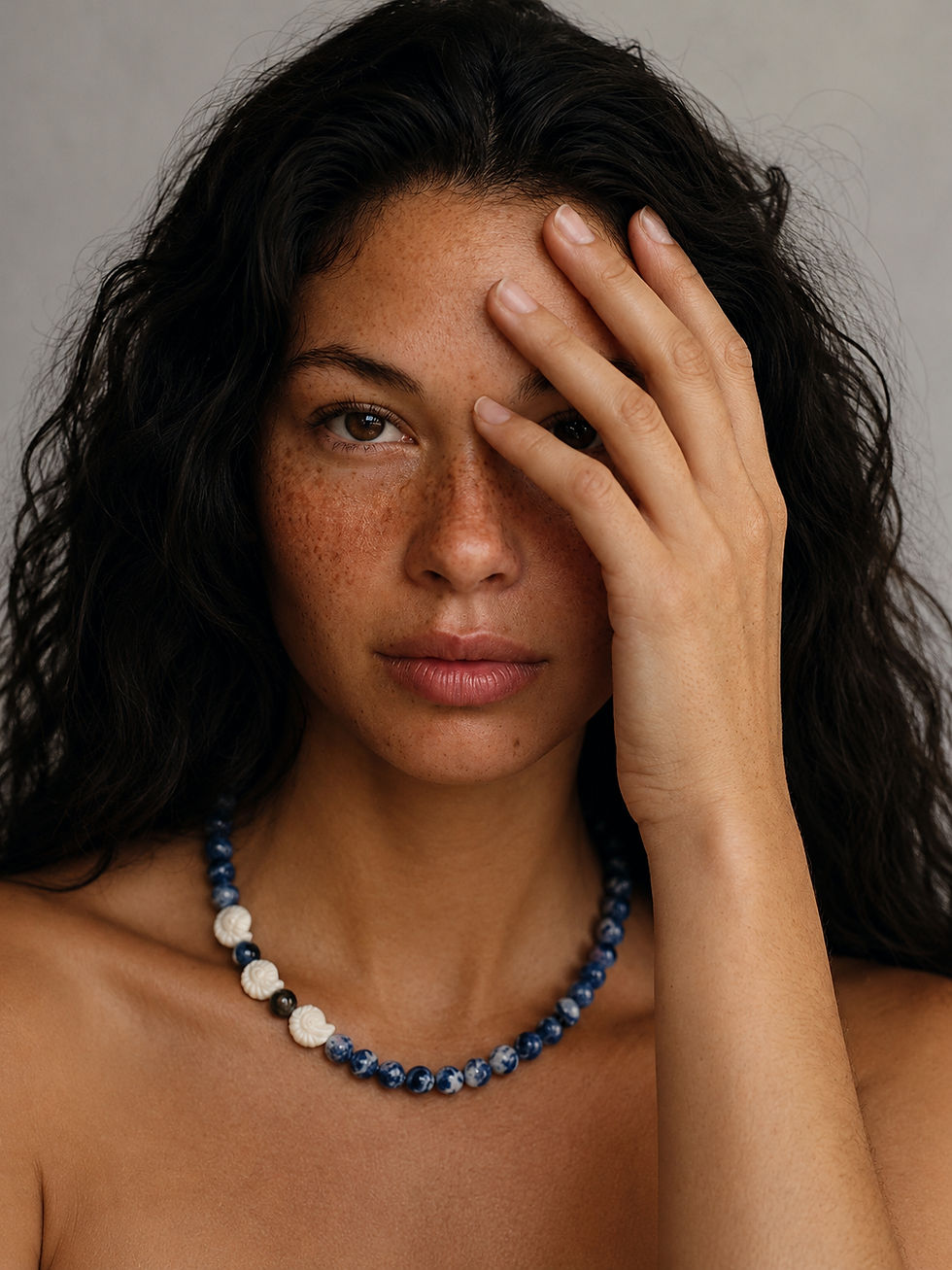 Close-up portrait of model wearing Sodalite Beaded Necklace with blue sodalite gemstone beads and white shell details.