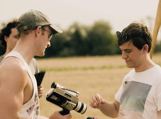 An assistant director and director handling a super 8 camera on a film set.