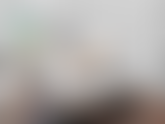 Bright white bedroom with upholstered bed, patterned rug, dresser, and window shutters.