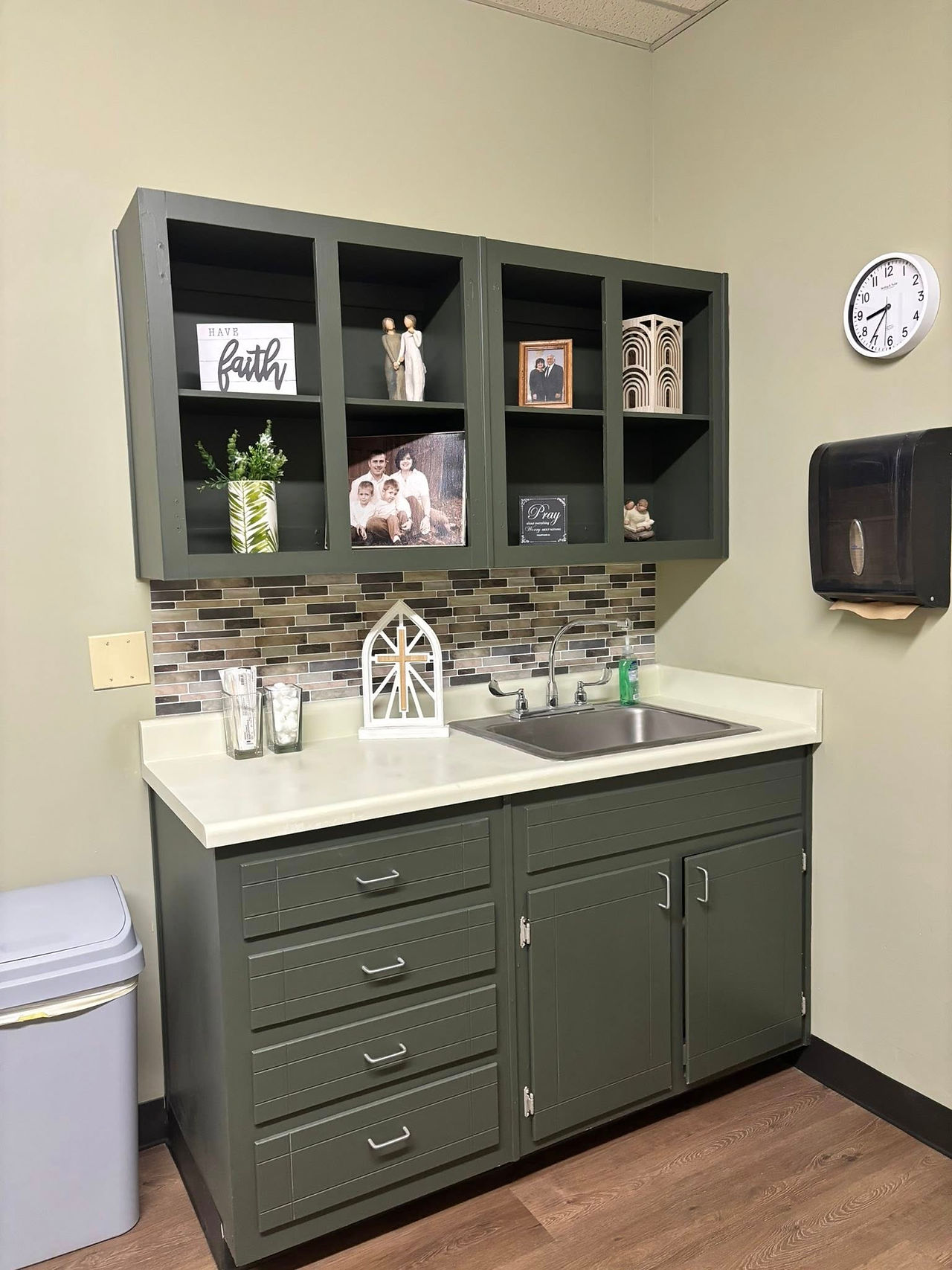 Cabinet and sink in exam room painted sage green with personal, decorative touches