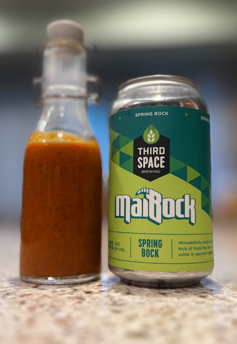 A beer and a bottle of wing sauce