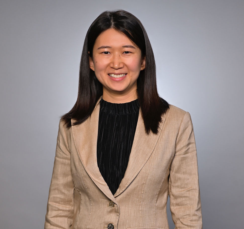 Smiling woman with long dark hair wearing a beige blazer.