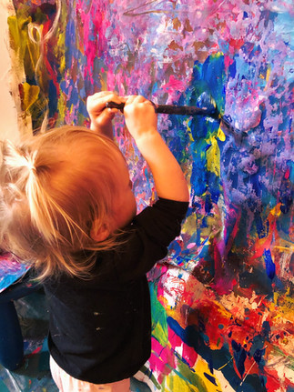 Toddler painting on a large canvas.