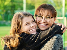 Mother and daughter showing affection embracing each other with a hug outdoors