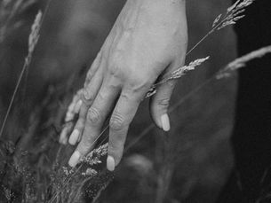 A hand gently brushing through tall grass in a field, in black and white â evoking slowness, calm, and letting go