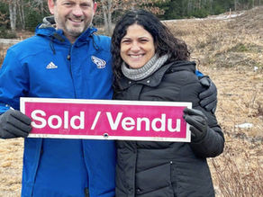couple showing sold sign in front of land