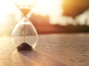 Un sablier posé au sol, avec le sable qui s’écoule lentement, symbolisant le passage du temps et le changement une seconde à la fois.