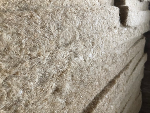 Close-up of stacked hemp insulation panels, showcasing their natural fibre texture and density.