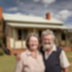 a middle aged ugly but happy australian couple standing outside a house in a rural area w