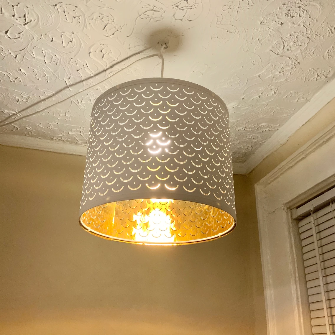 White cylindrical hanging light with gold insides and scalloped design