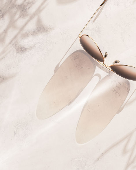 Product photograph of a pair of Ray-ban Aviator sunglasses from above with a strong shadow.