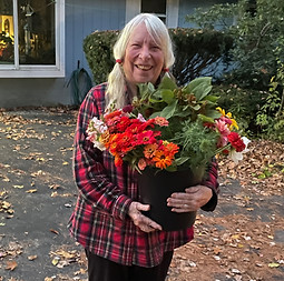 A woman with white hair holds a bucket of flowers