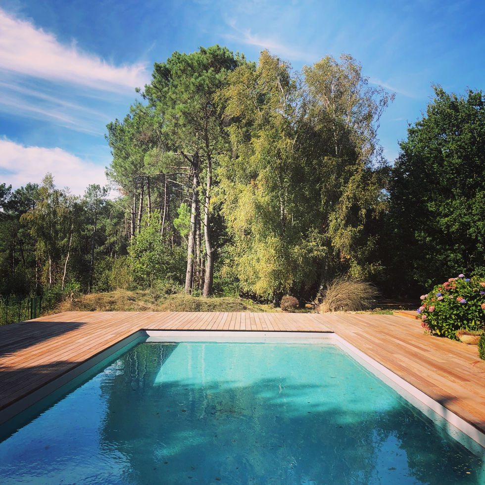 alt="Bassin turquoise et terrasse en bois entourée d’arbres, rénovés par Ty Méno à Rennes"