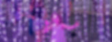 Young girl surrounded by hanging strands of purplish lights in an installation by Light Riders