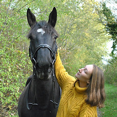 Cavalière qui regarde et caresse son cheval en forêt