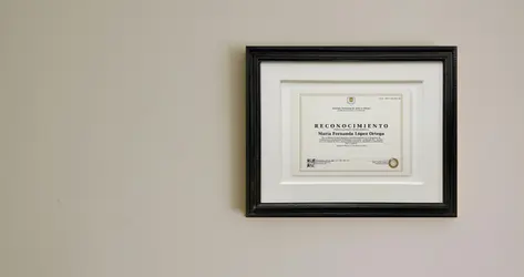 Diploma de reconocimiento profesional enmarcado con moldura negra clásica y doble paspartú blanco.