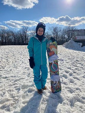 meagen standing at the top of a mountain with her snowboard
