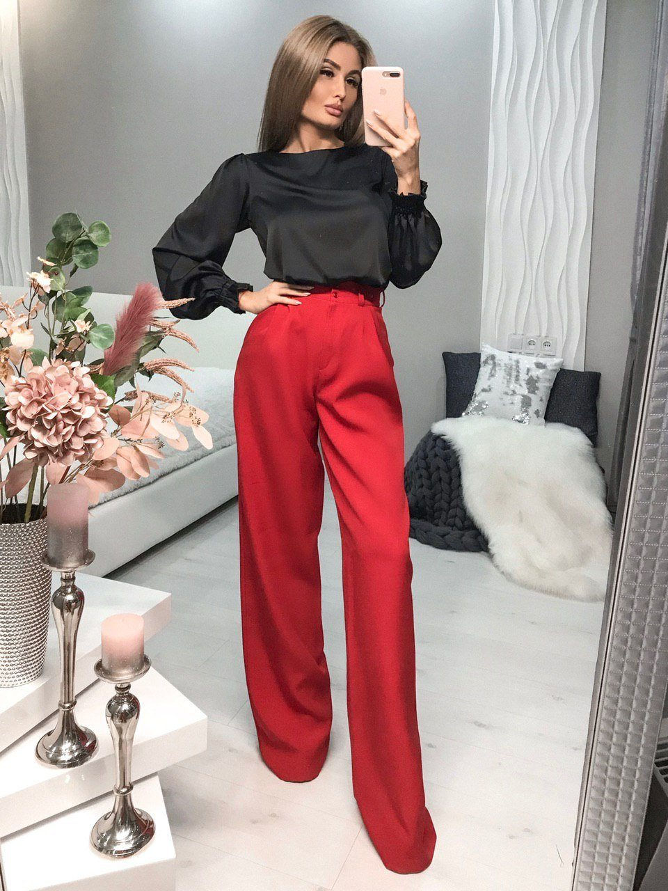 Miniatura: Mujer posando con blusa negra satinada y pantalones rojos palazzo.