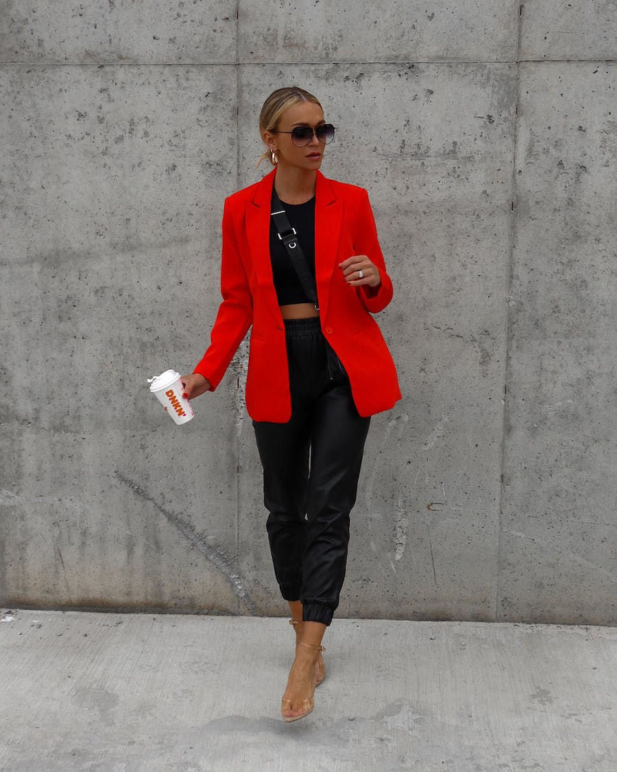 Miniatura: Mujer elegante con blazer rojo, pantalón negro, gafas y café Starbucks.