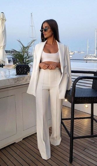 Miniatura: Mujer elegante con conjunto blanco en un lujoso yate al atardecer.
