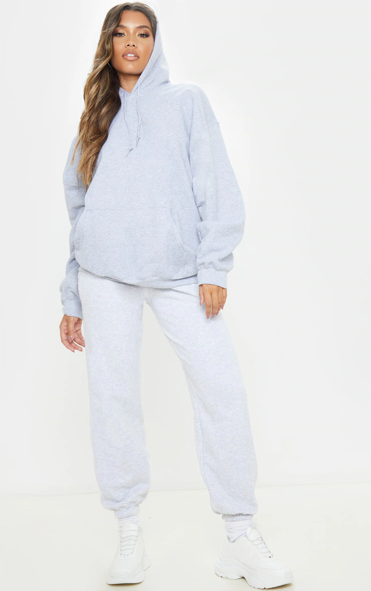 Miniatura: Persona vistiendo una sudadera con capucha gris extragrande y pantalones deportivos.