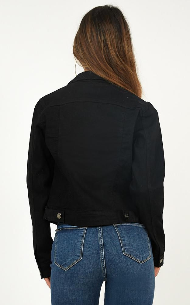 Miniatura: Mujer de espaldas con campera de jean negra y jeans azules.