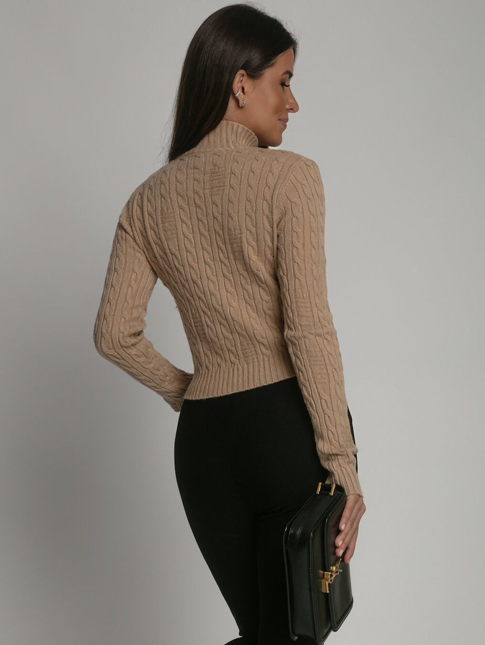 Miniatura: Mujer de espalda vistiendo suéter beige tejido ceñido y pantalón negro.