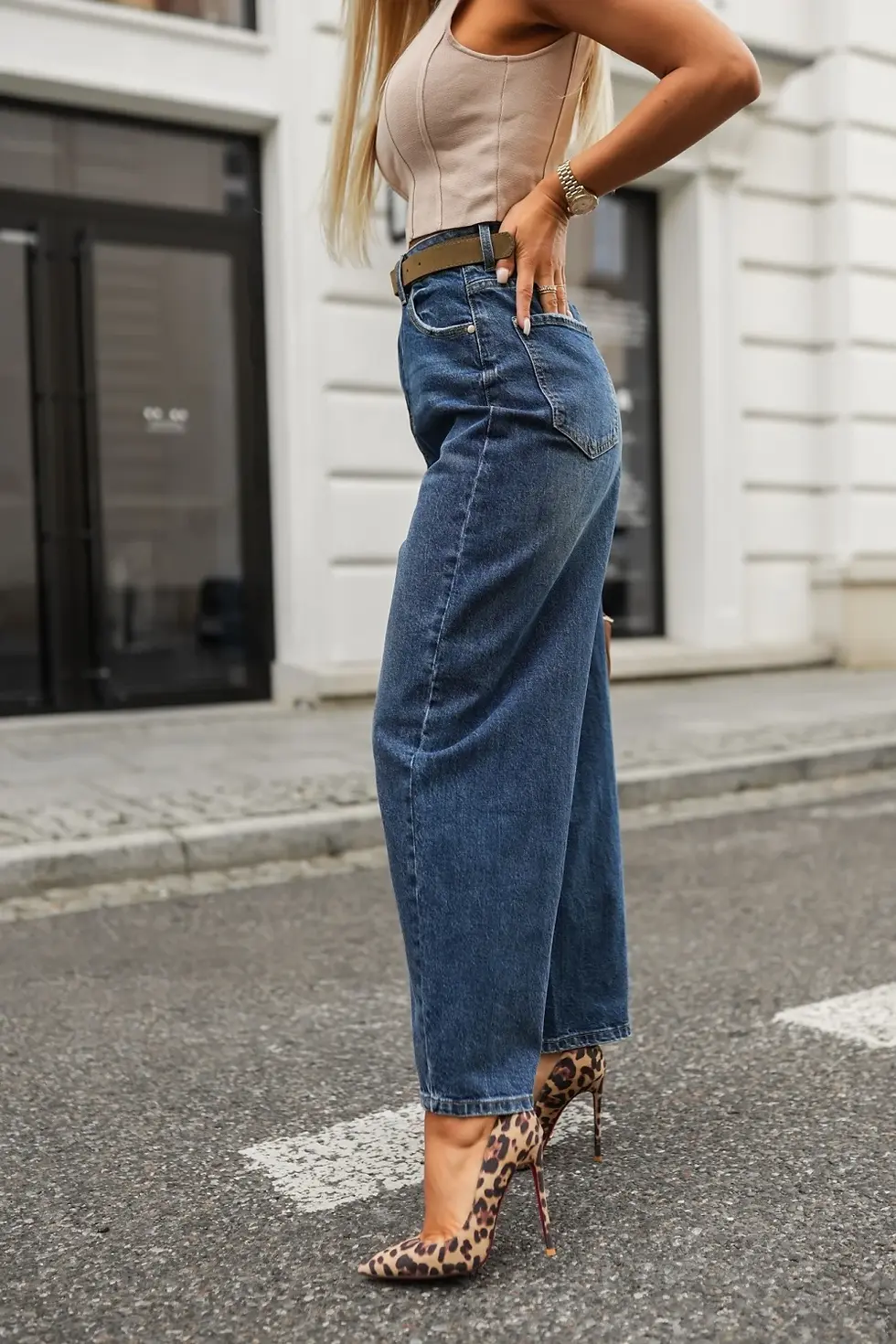 Miniatura: Mujer vistiendo pantalón vaquero azul oscuro de pierna ancha sobre acera.