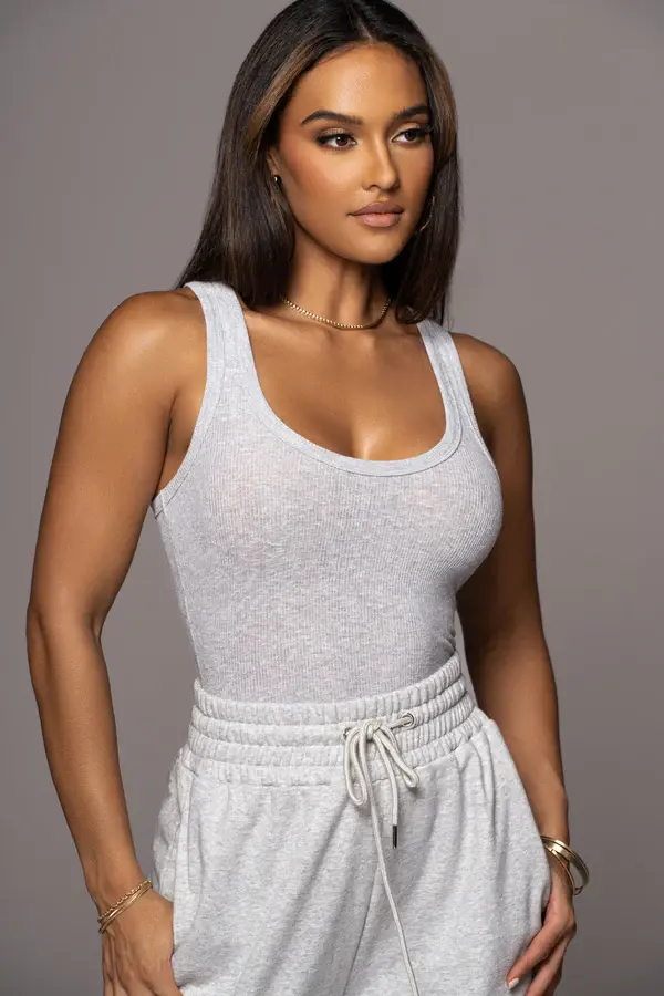 Miniatura: Mujer joven con camiseta sin mangas gris casual y pantalones deportivos cómodos.