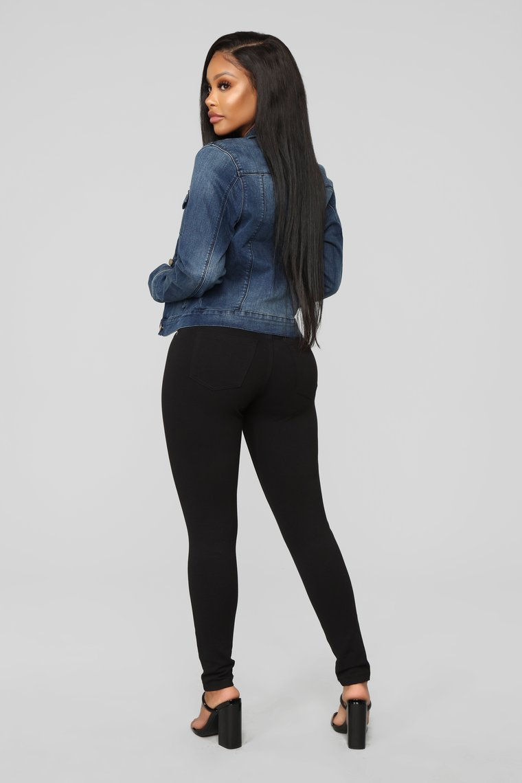 Miniatura: Mujer de espalda con chaqueta vaquera azul y pantalones negros ajustados.