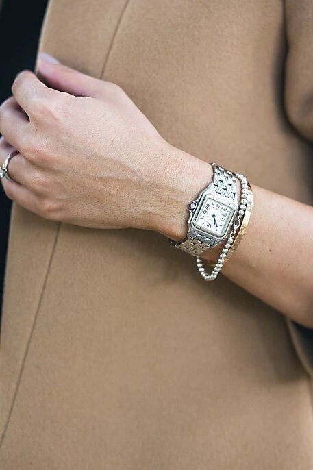 Miniatura: Muñeca femenina con reloj plateado elegante, pulsera de cuentas y anillo.