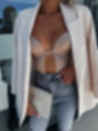 Mujer con body beige, jeans, blazer y bolso clutch YSL.