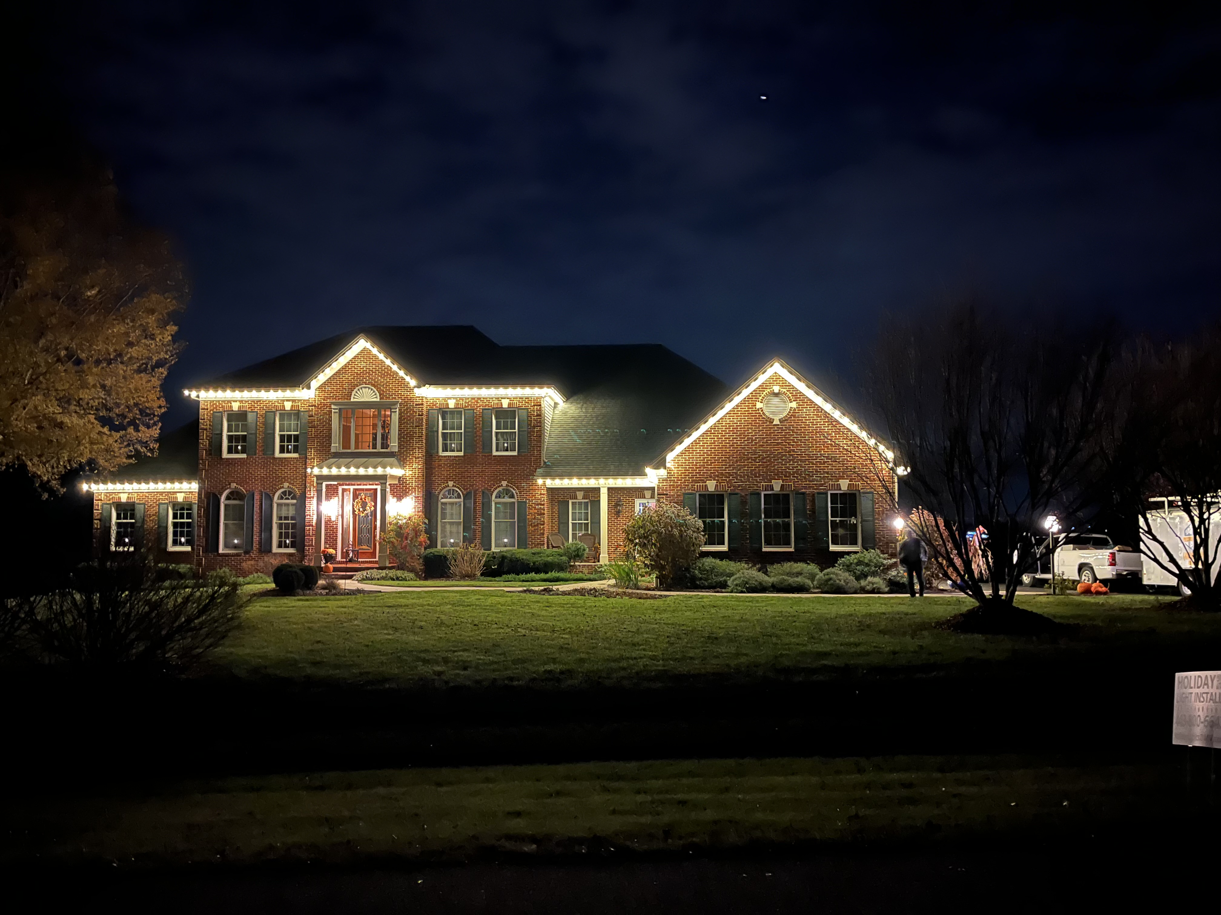 Real completed warm-white roofline Christmas light installation on a brick Maryland home