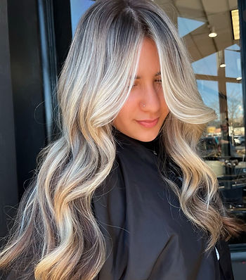 A young girl with long blonde hair and dimensional hair color done at Something You Beauty in Paoli
