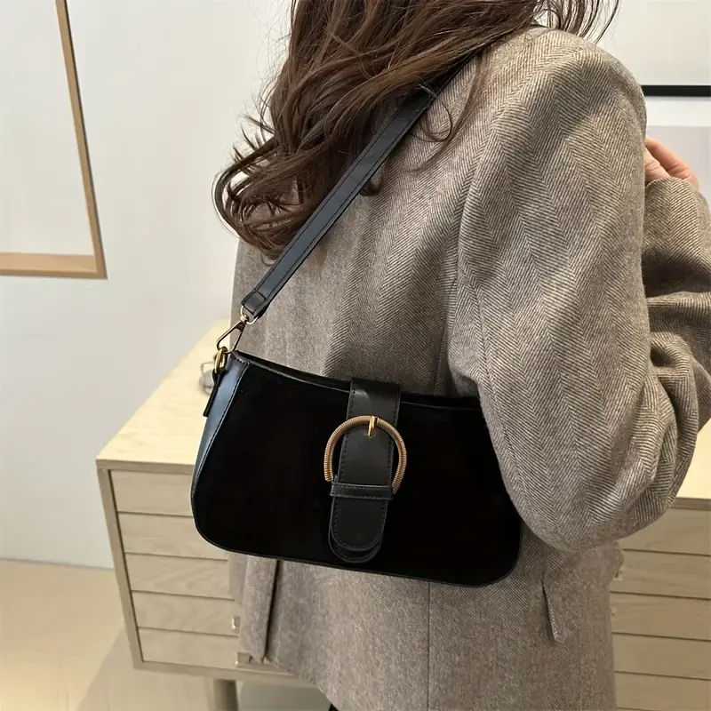 Thumbnail: Woman in jacket carrying a black shoulder bag with a prominent buckle.