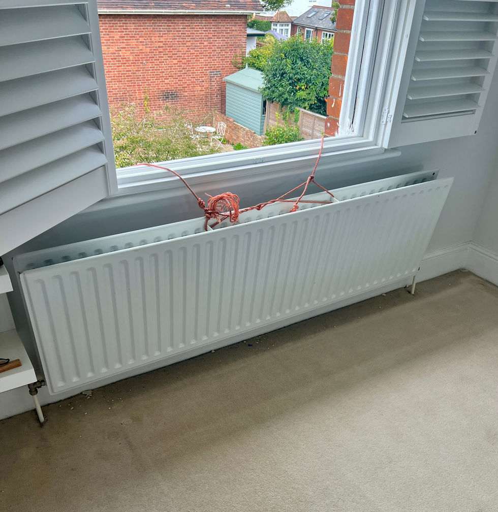 Radiator temporarily secured under window before draining and removing wall brackets – Reigate handyman service