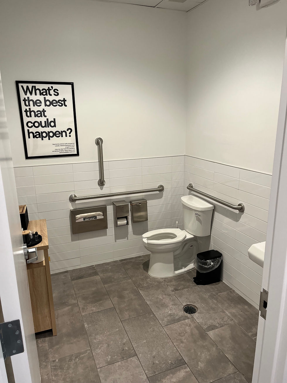 Clean, modern ADA-compliant restroom with tiled floors and motivational signage.