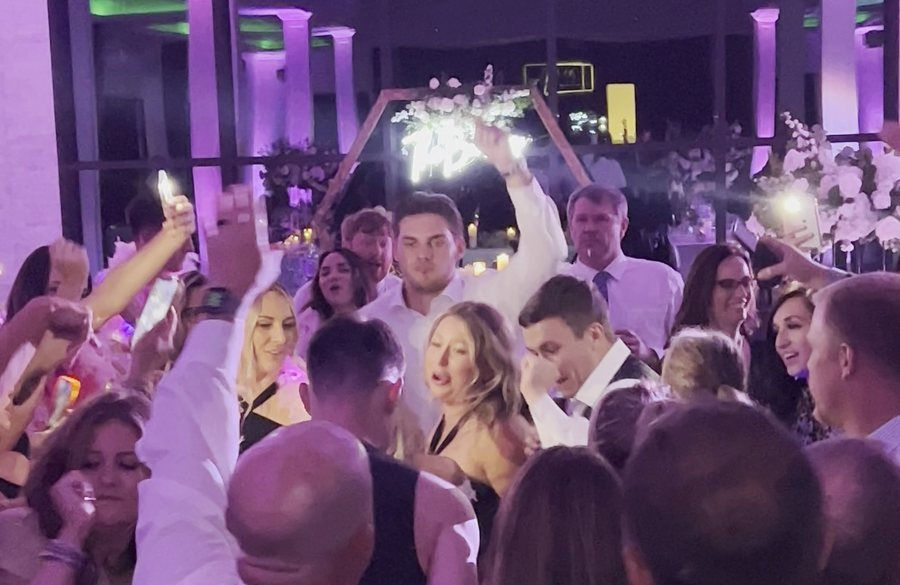 Packed wedding dance floor under purple uplighting by AMP Events and Lighting in Houston