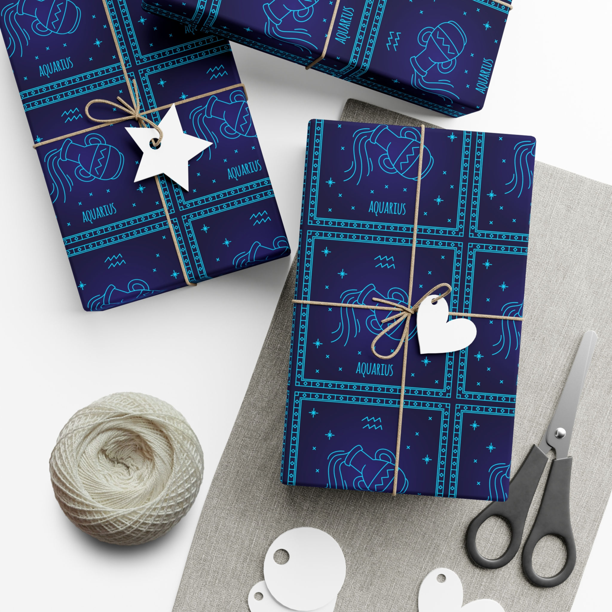 Wrapped gifts with blue pattern and tags on white surface with scissors and string