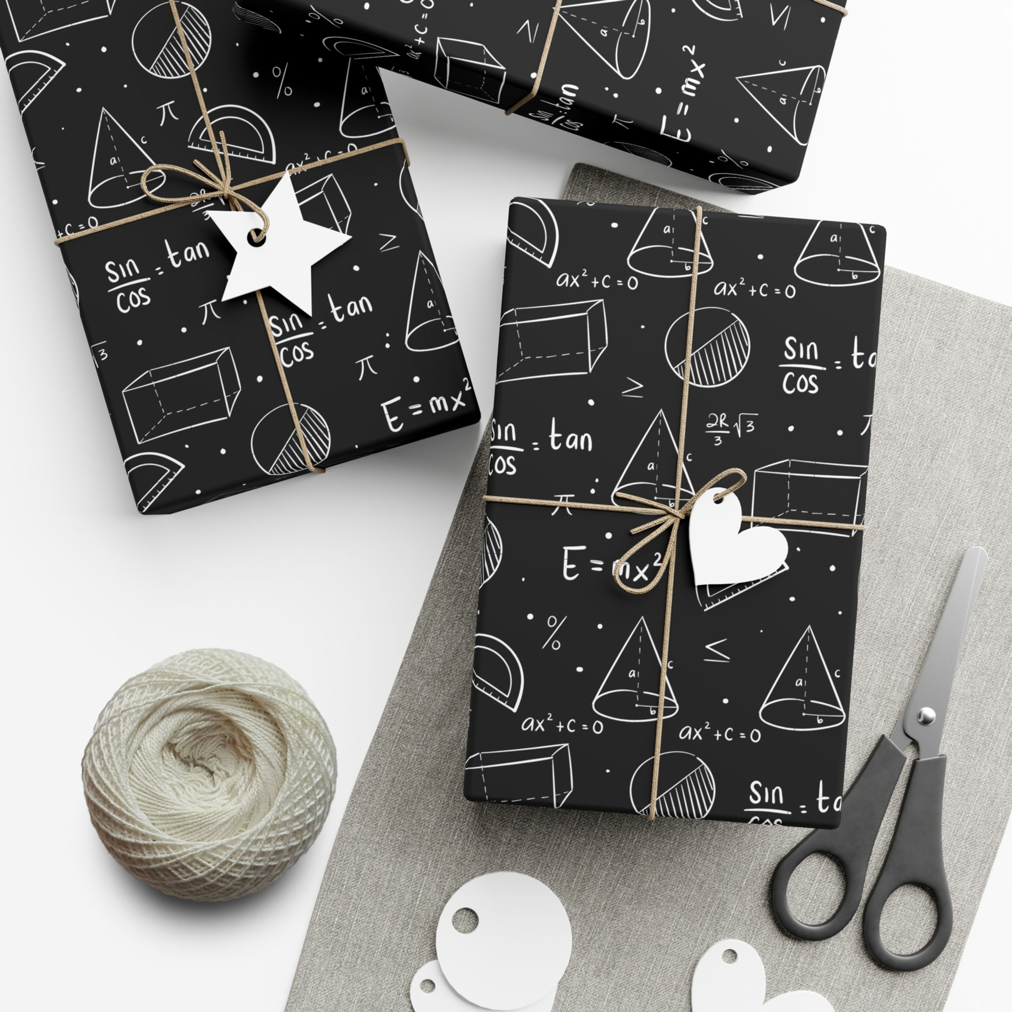 Wrapped gifts with math equations and shapes, scissors, and string on a table.